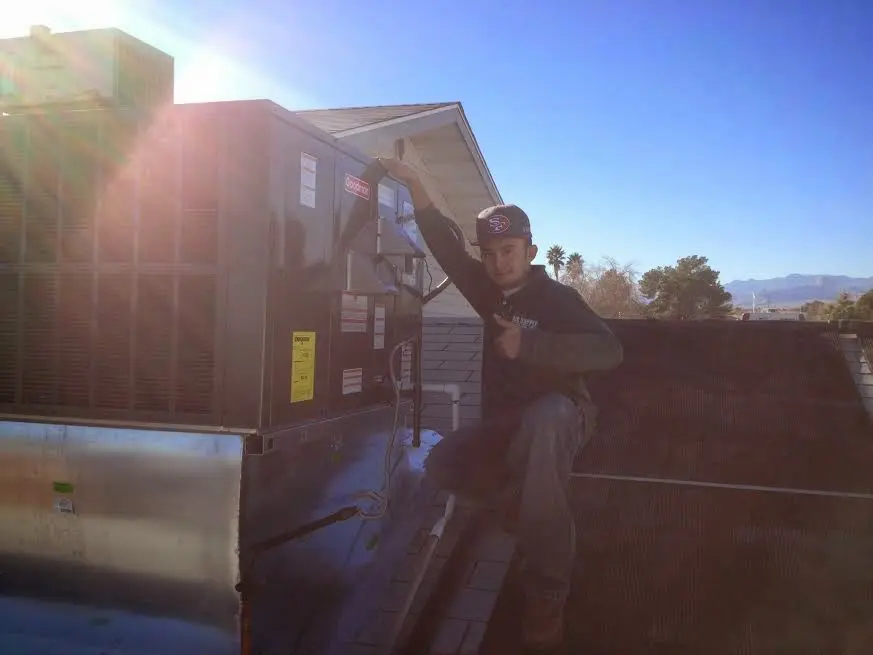 HVAC technician performing AC Tune-Up on a rooftop unit in Penfield