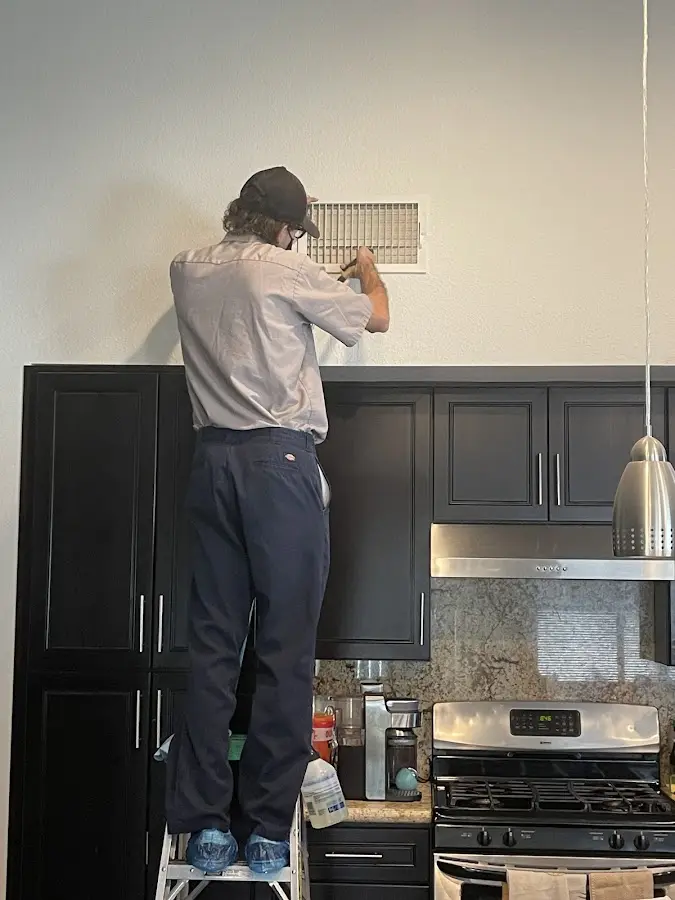Technician inspecting an air vent during HVAC service in Penfield